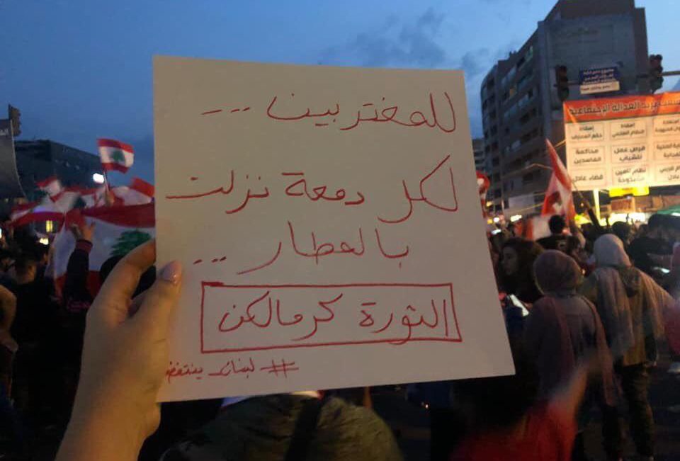 A sign that reads "To the expats, to every tear that was shed in the airports, the revolution is for you."