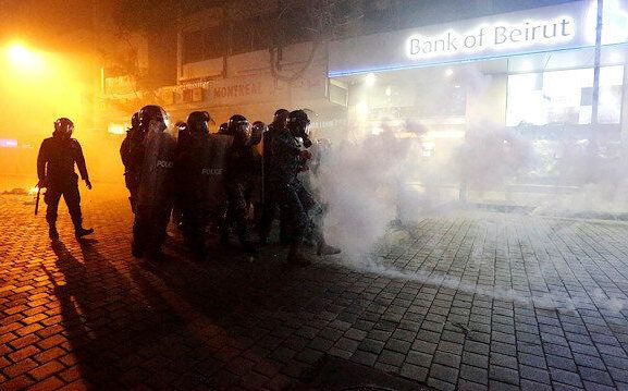 Riot police stand behind riot shields in a cloud of tear gas during protests against the economic crisis outside a Bank of Beirut office in Beirut. January 14, 2020. (PHOTO: Reuters / Mohamed Azakir) / Week of Anger / Protesters and security forces clash