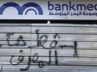 “Down with the rule of the bank” reads this graffiti on the door of Bankmed, one of the top five banks in Lebanon. A default deals a major blow to the banking system in Lebanon. (AP / Financial Times)