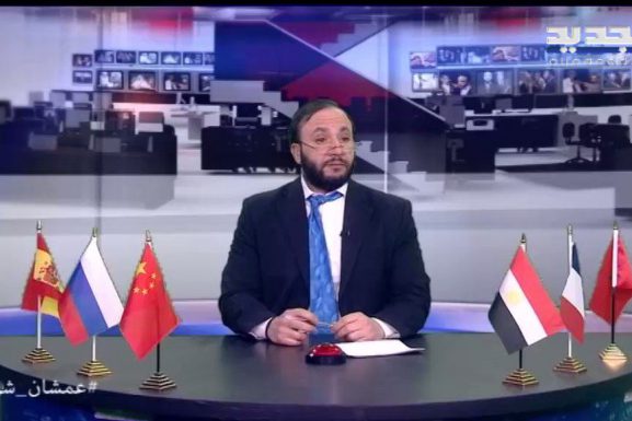 Wissam Saad sits at his desk in his persona at Al Jadeed