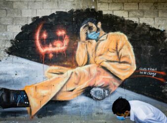Man in face mask walks past a mural that reads "We Are Tired" in Tripoli, Lebanon. (Photo: AFP)