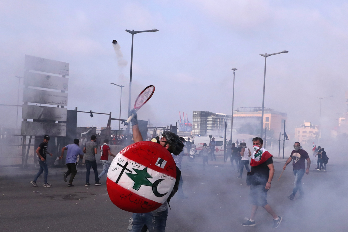 An anti-government protester throws back tear gas at riot policemen with a tennis racket in Beirut, Lebanon on June 6, 2020. (Photo: Al-Jazeera via AP Photo/Bilal Hussein)