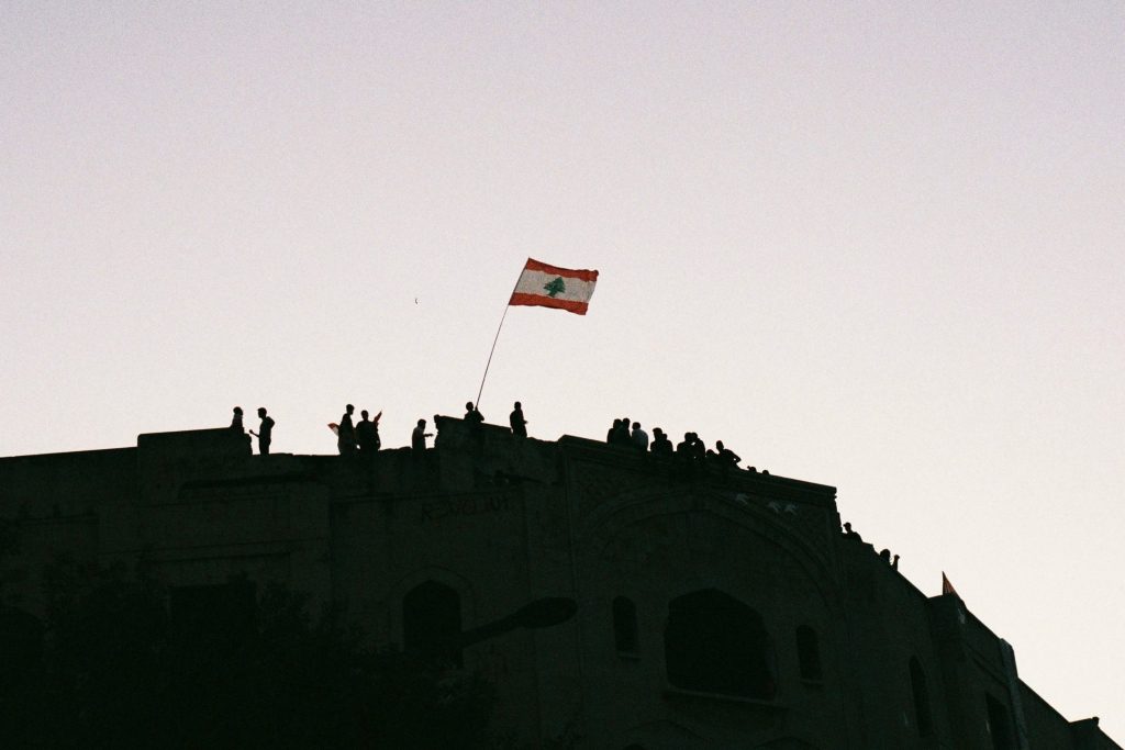 Protesters in Beirut stand on rooftops and wave a Lebanese flag. (Photo: Marylin Chahine) | Protest adapting article