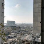 Reconstruction article: The Beirut port as seen through the shattered window of a nearby home after the explosion that decimated the Lebanese capital (Photo: Michael Abounabhan)