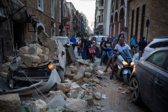 People ride past a destroyed car following the large explosion on August 4, 2020 in Beirut, Lebanon. (Photo: Arabian Business via Daniel Carde/Getty Images)