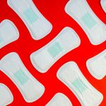 Aesthetic background showing pads lined up against a red background. Lockdowns, period, and menstrual cycle article.