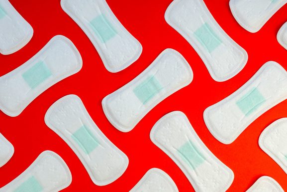 Aesthetic background showing pads lined up against a red background. Lockdowns, period, and menstrual cycle article.