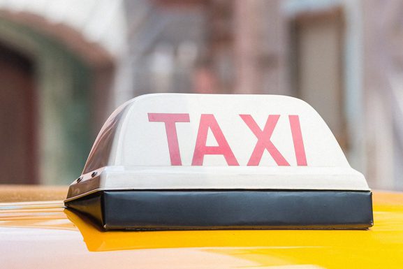 Service taxi article in Lebanon. Close up of taxi sign on top of yellow car with a blurred background.