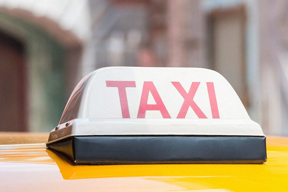 Service taxi article in Lebanon. Close up of taxi sign on top of yellow car with a blurred background.