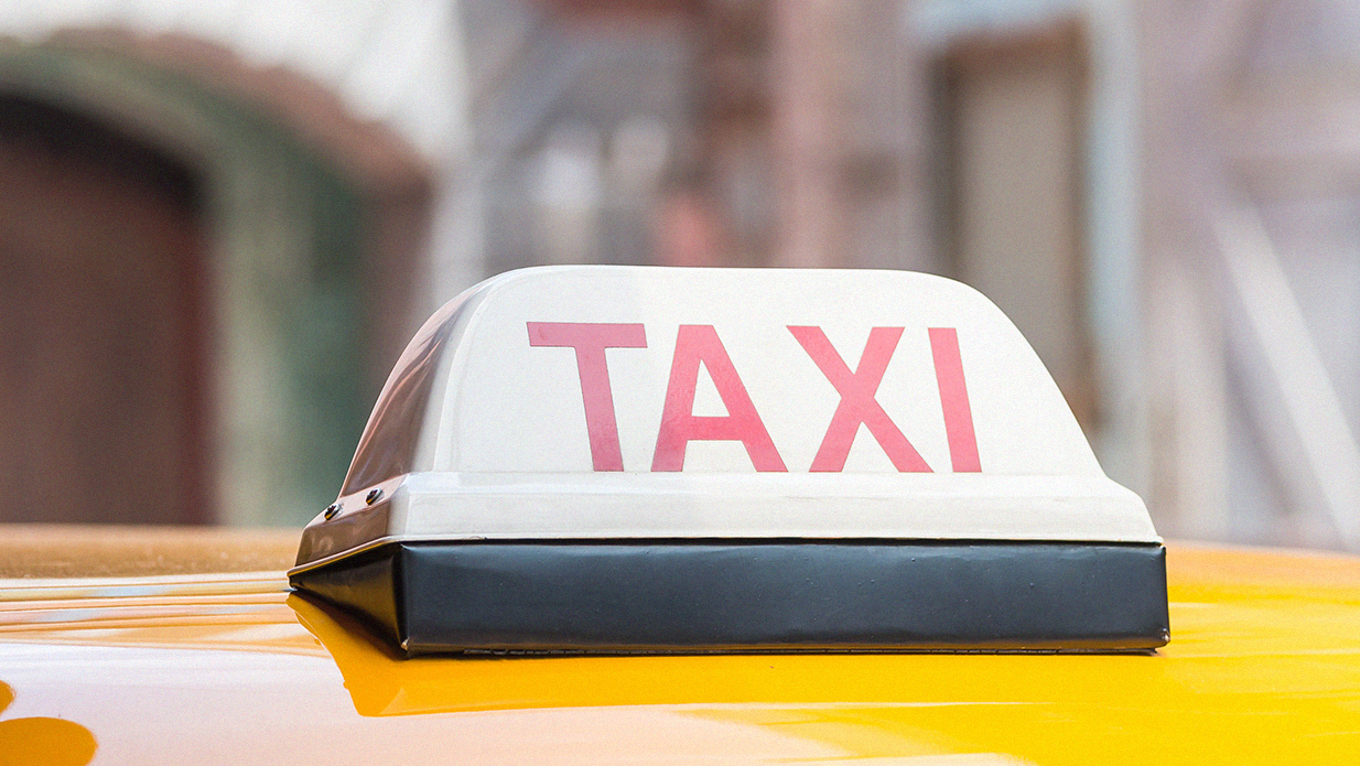 Service taxi article in Lebanon. Close up of taxi sign on top of yellow car with a blurred background.