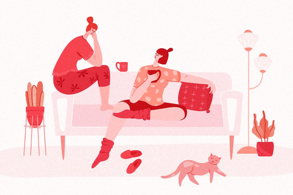 A lesbian couple sits on a couch and chats in their living room