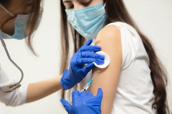 Woman in face mask receiving a COVID-19 vaccine jab