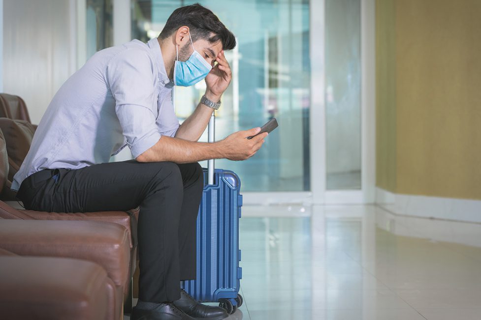 Businessman sits in hotel lobby alone with luggage.