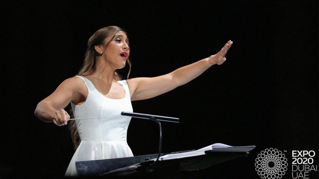 Lebanese conductor Yasmina Sabbah stands at a podium