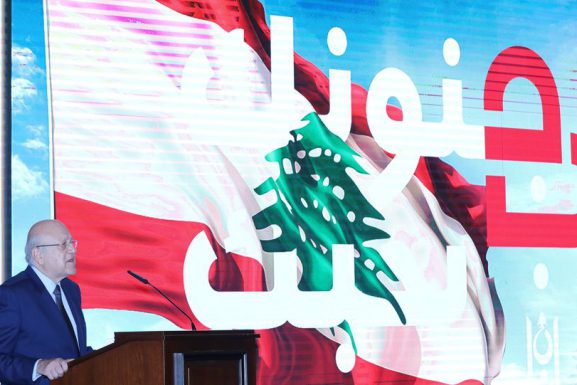 Lebanon's Prime Minister stands near "We love you in your madness" slogan on November 4, 2021. (Photo: Dalati & Nohra)