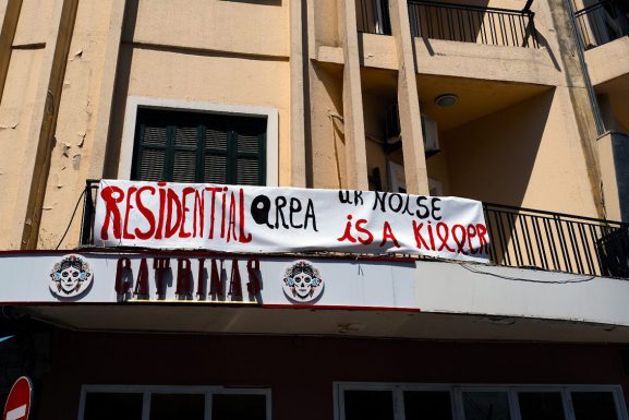 A banner that reads "Residential area, ur noise is a killer" hangs on a building in Mar Mikhael. Beneath the sign is the restaurant Catrinas.