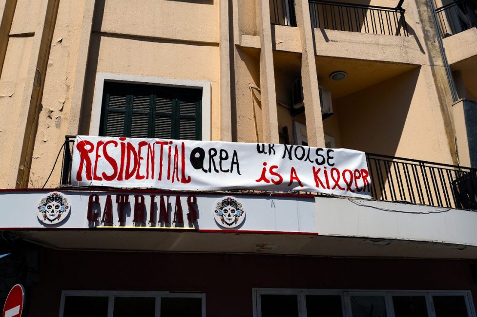 A banner that reads "Residential area, ur noise is a killer" hangs on a building in Mar Mikhael. Beneath the sign is the restaurant Catrinas.