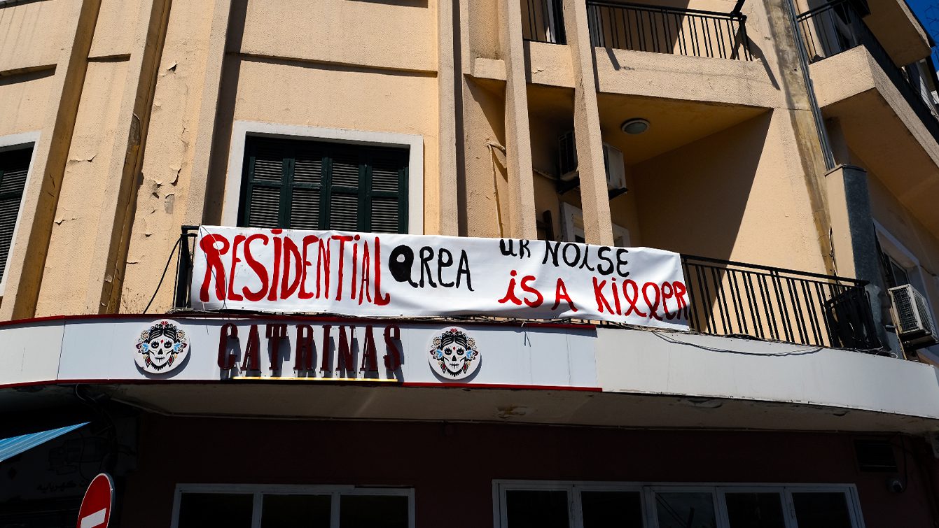 A banner that reads "Residential area, ur noise is a killer" hangs on a building in Mar Mikhael. Beneath the sign is the restaurant Catrinas.