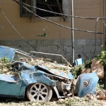 Ablue car is wrecked at the side of the road, covered in debris from a nearby building after the Beirut blast.