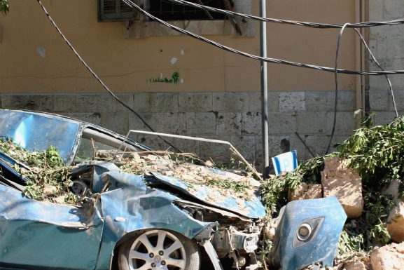 Ablue car is wrecked at the side of the road, covered in debris from a nearby building after the Beirut blast.